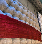 Claret Cotton-Blend Cable-Knit Throw: Red cable-knit throw spread over a tufted sofa.