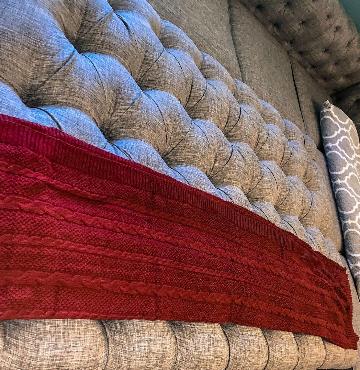 Claret Cotton-Blend Cable-Knit Throw: Red cable-knit throw spread over a tufted sofa.