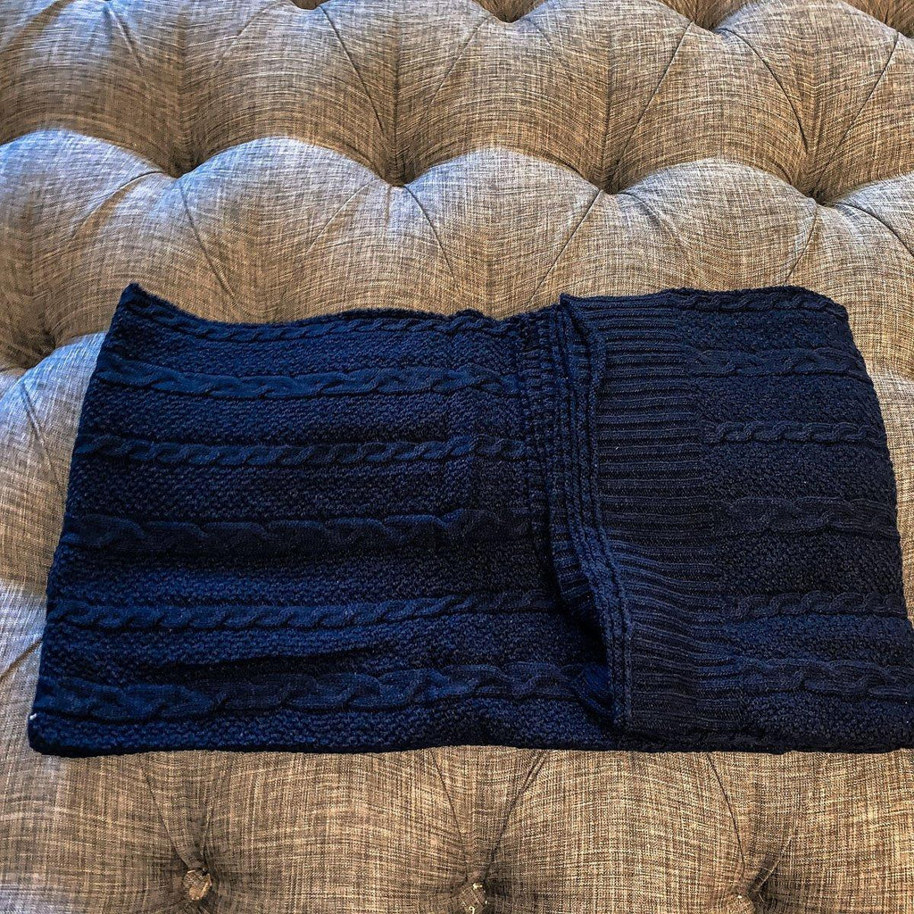 Claret Cotton-Blend Cable-Knit Throw: Blue cable-knit throw folded across a tufted sofa.