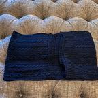 Claret Cotton-Blend Cable-Knit Throw: Blue cable-knit throw folded across a tufted sofa.