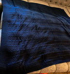 Claret Cotton-Blend Cable-Knit Throw: Blue cable-knit throw spread on a wooden bench.