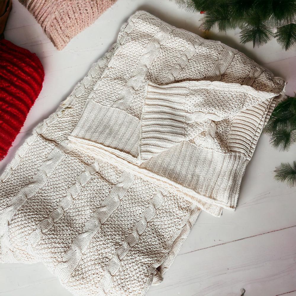 Claret Cotton-Blend Cable-Knit Throw: Cream cable-knit throw draped over a sofa.