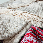 Claret Cotton-Blend Cable-Knit Throw: Close-up of cream cable knitting and fringe beside patterned fabric.