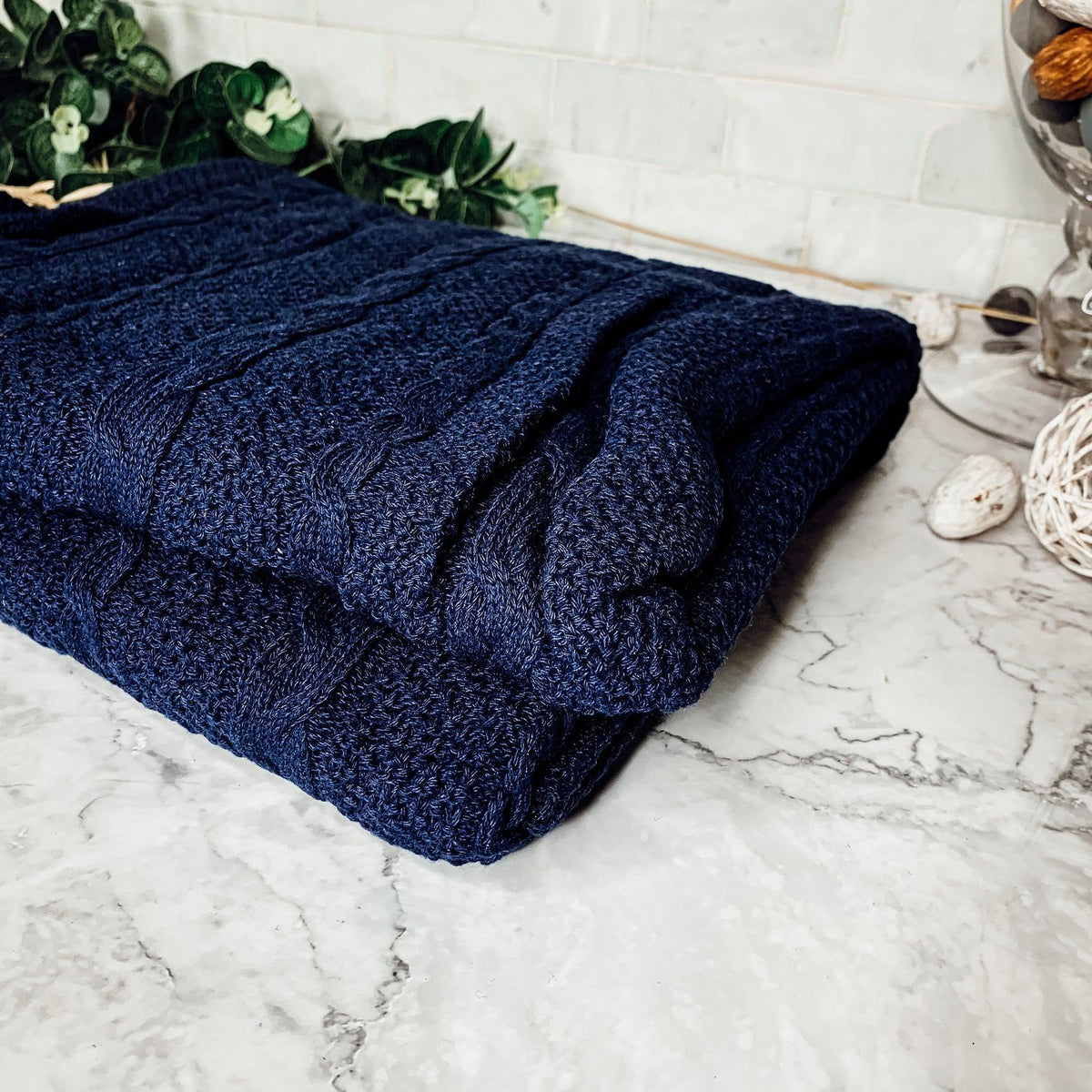 Claret Cotton-Blend Cable-Knit Throw: Blue cable-knit throw spread across a sofa.