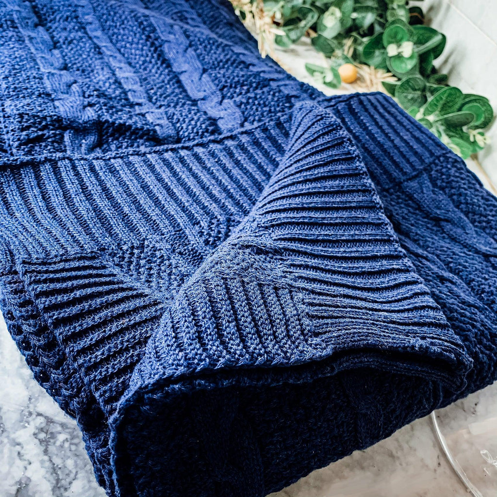 Claret Cotton-Blend Cable-Knit Throw: Close-up of blue cable knitting and ribbed edge.