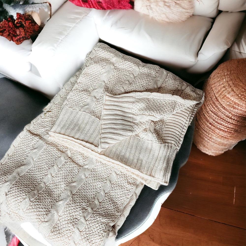 Claret Cotton-Blend Cable-Knit Throw: Cream cable-knit throw spread along a white sofa.