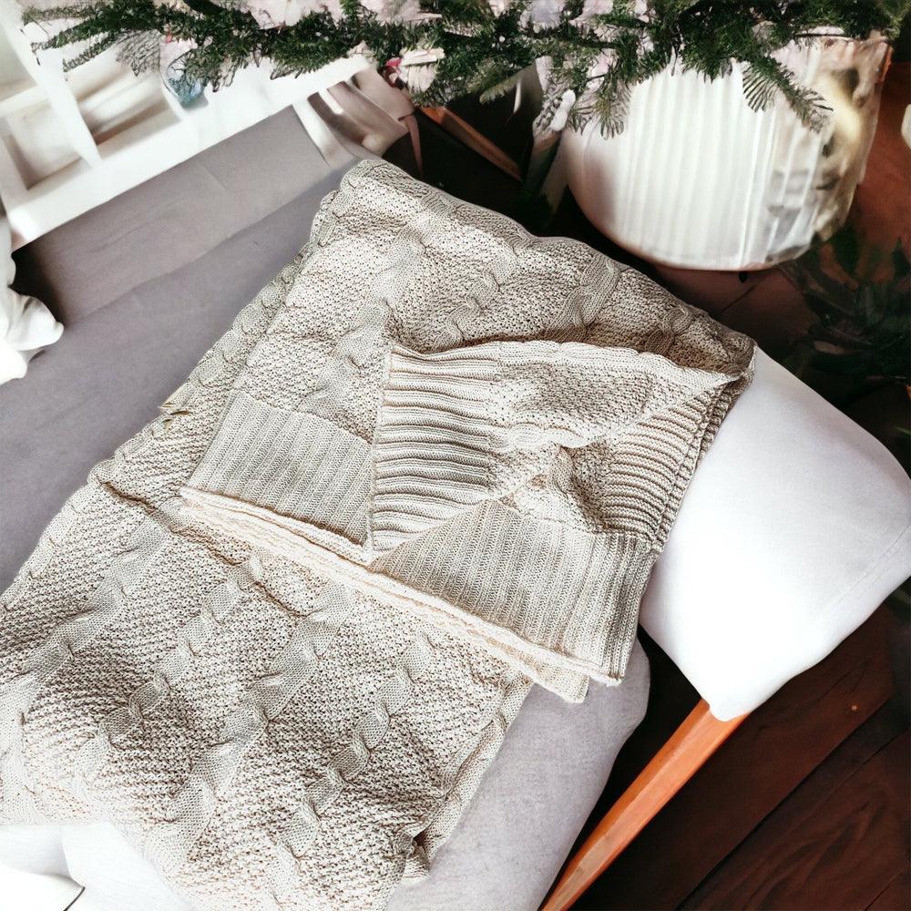 Claret Cotton-Blend Cable-Knit Throw: Overhead view of a cream cable-knit throw on a sofa.