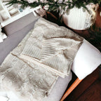 Claret Cotton-Blend Cable-Knit Throw: Overhead view of a cream cable-knit throw on a sofa.