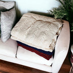 Claret Cotton-Blend Cable-Knit Throw: Cream throw folded over blue and red throws on a chair.
