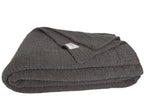The Nest Microfiber Throw — 75 × 52 in: Folded dark throw with a visible fabric label.