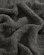 The Nest Microfiber Throw — 75 × 52 in: Close-up of the dark gray textured fabric.